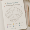 Un bullet journal ouvert sur une page illustrant un thème marin pour juin avec des coquillages et des vagues.